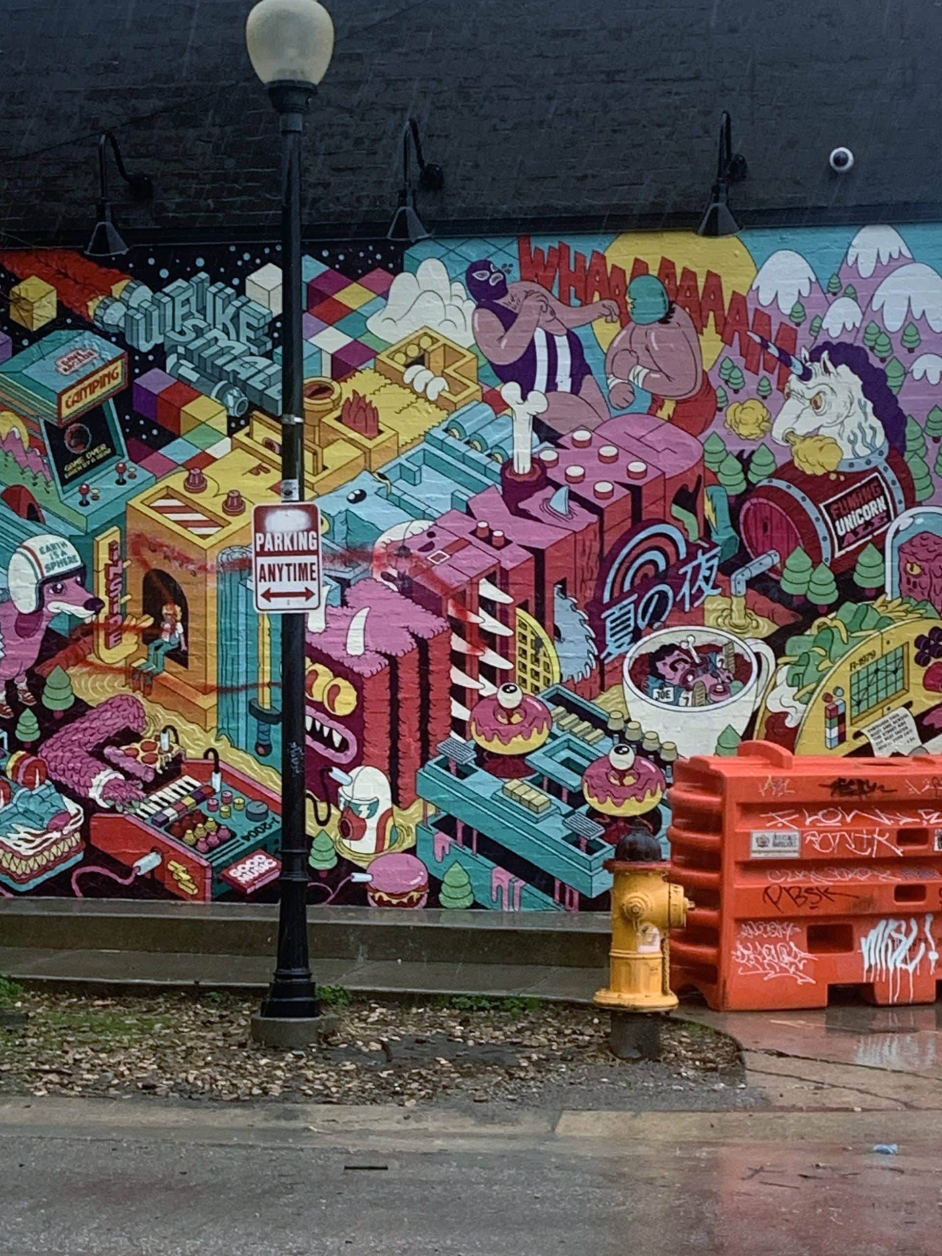 A colorful mural painted on a black brick wall