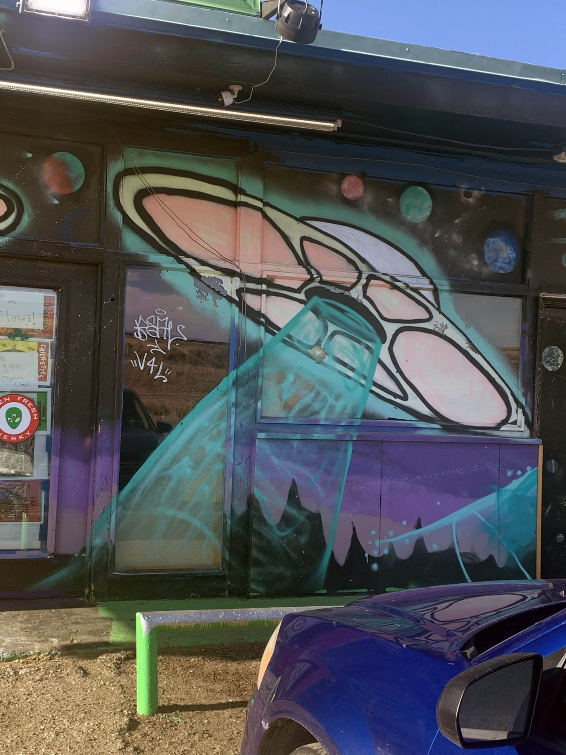 a colorful painting of a UFO on a metal wall