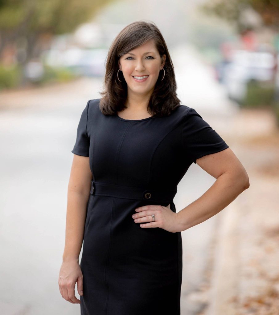 A headshot of a woman in business attire, blurry background