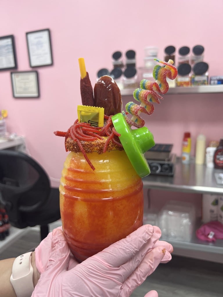 A Mexican snack called Chamoyada. It is a yellow and red beverage topped with Mexican snacks.